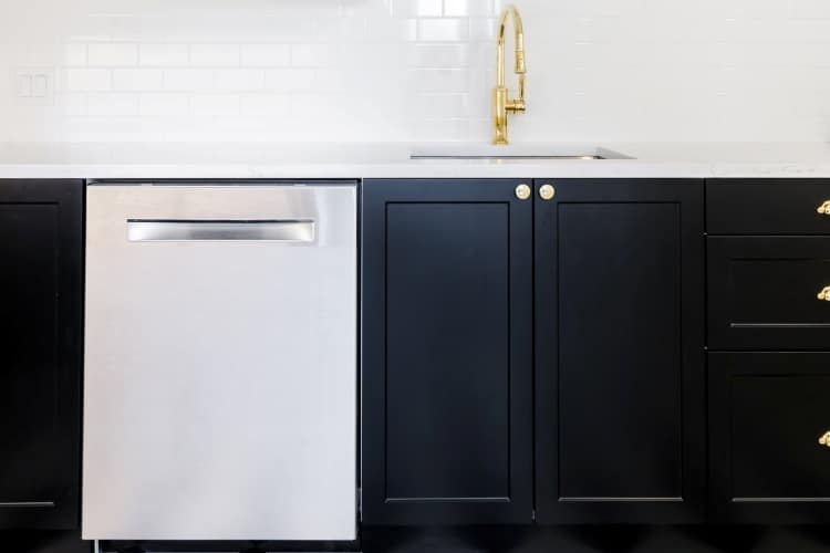 Black kitchen cabinets contrasted with white walls and gold hardware